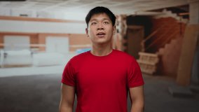 Young man in red shirt expresses surprise and excitement at an indoor construction site, showcasing emotions amidst a work environment. - Powered by Shutterstock - Get 15% off with code: PIKWIZARD15
