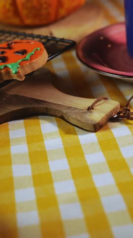 Right to left horizontal pan on dark wood table with Halloween cookies and carved pumpkin. Autumn light, warm atmosphere and space for copy space.