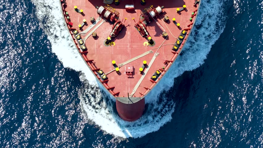 Aerial overhead view of a bow from a large container cargo or tanker ship sailing with speed over the ocean