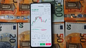 Bitcoin trading on a smartphone screen, placed over Euro bills, symbolizing the convergence of digital currencies and traditional European financial systems - Powered by Shutterstock - Get 15% off with code: PIKWIZARD15