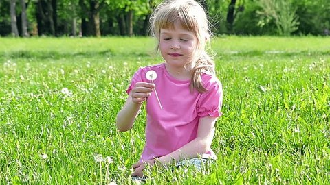 Little girl holding a dandelion in the park. Slow motion, high speed camera