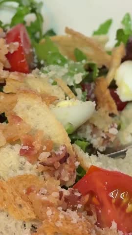 Eating Caesar salad with fork. Healthy salad made of chicken fillet, lettuce, tomatoes, quail eggs, croutons, parmesan cheese in a plate