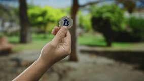 Man holding bitcoin outdoors with green park scenery in background highlighting cryptocurrency in nature - Powered by Shutterstock - Get 15% off with code: PIKWIZARD15