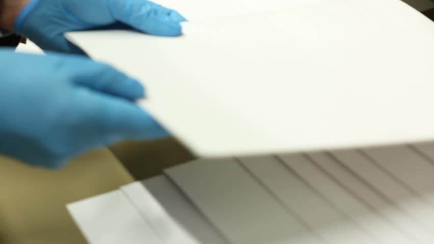 Gloved hands carefully examine old, fragile historical documents and newspaper clippings. Archiving and preserving vintage papers for research, history, and knowledge.