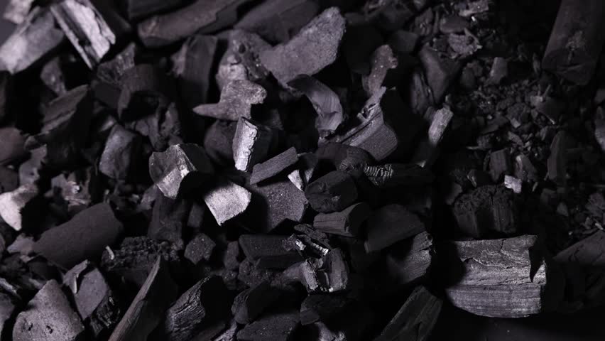 Man with black coals over pile, above view