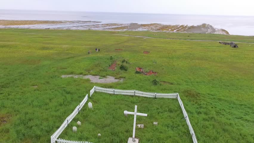 Five People Walk to a Small Family Cemetery Enclosed with a Wooden Fence Next to the Beach at Anse-aux-Fraises