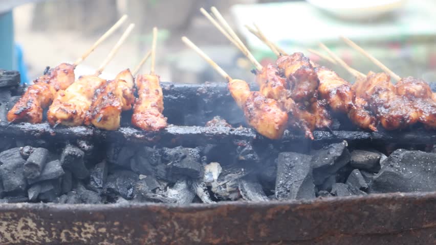 Grilling satay over charcoal embers is an authentic indonesian culinery speaciality. Processed making chicken satay.