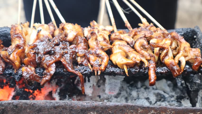 Grilling satay over charcoal embers is an authentic indonesian culinery speaciality. Processed making chicken satay.