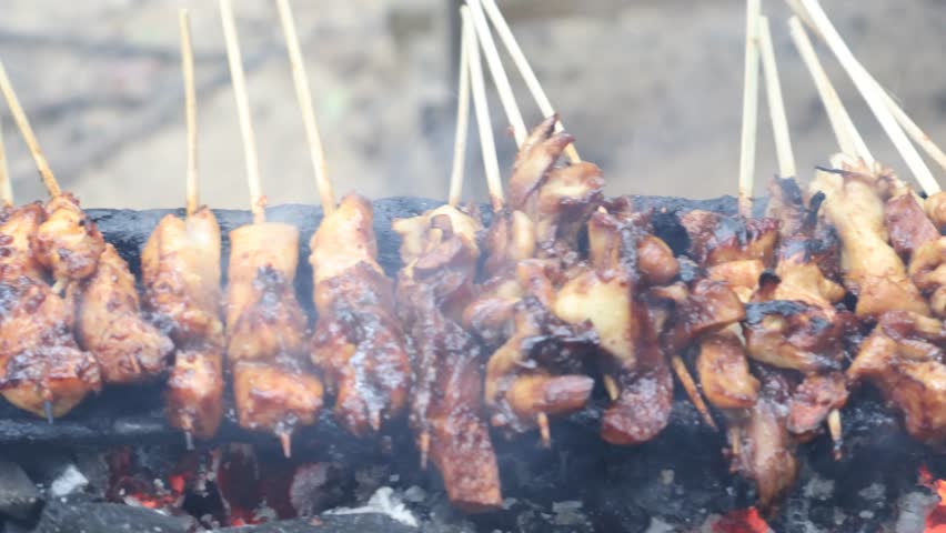 Grilling satay over charcoal embers is an authentic indonesian culinery speaciality. Processed making chicken satay.