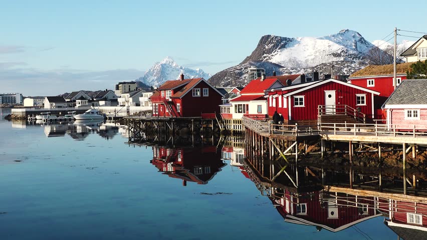 A red cabin with a grassy roof stands near the water