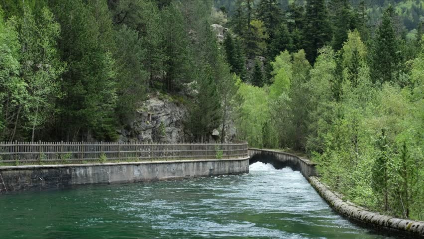Swift, Wild Mountain River Flowing between Man-made Concrete Banks. Alpine Landscape in "Aigüestortes i Estany de Sant Maurici National Park". Catalan Pyrenees, Spain.