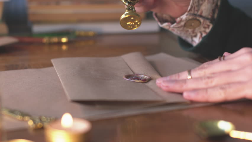 A girl seals a letter and prepares it for mailing. Pressing a wax seal. Mailing a letter. Hands sealing a letter with hot red wax. - Powered by Shutterstock - Get 15% off with code: PIKWIZARD15