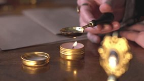 Close-up of a woman heating wax in a gold spoon on a candle, preparing to seal a letter with an antique seal. sending mail. - Powered by Shutterstock - Get 15% off with code: PIKWIZARD15