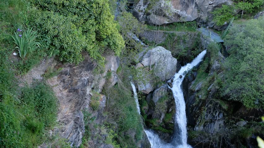 Two Merging Mountain Streams. Waterfall's Observation Deck. Green, Lush Vegetation. Mountain Catalan Village in the Pyrenees. Evening Gnats in Dusk. Travel and Tourism. Highlands' Slow-paced Life.