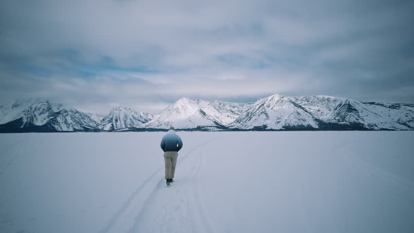 Man Walking on Snow Field to Teton Mountains Wyoming