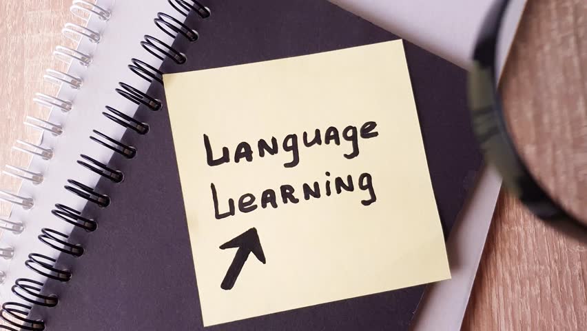 LANGUAGE LEARNING, text note note taking on a sheet of paper through a magnifying glass. Language learning,language education,concept.