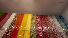 A vibrant assortment of colorful candies neatly arranged in transparent vertical tubes on a wall display inside a candy store. The image showcases a wide variety of textures and hues, including red - Powered by Shutterstock - Get 15% off with code: PIKWIZARD15