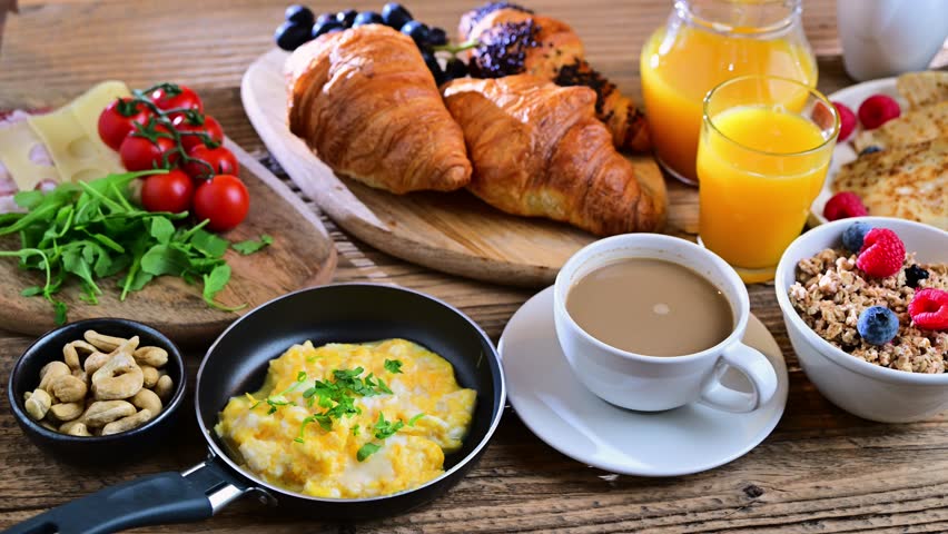 Breakfast served with coffee, orange juice, scrambled eggs, cereals, pancakes and croissants.