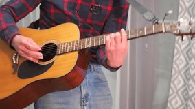 Close-up of a man in a red plaid shirt playing an acoustic guitar and gently swaying to the rhythm in a cozy indoor setting. Musical atmosphere at home, moment of personal joy and creative flow. - Powered by Shutterstock - Get 15% off with code: PIKWIZARD15