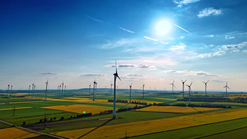Numerous wind turbines in the beautiful vast fields. Drone flight over the plantation in the countryside.