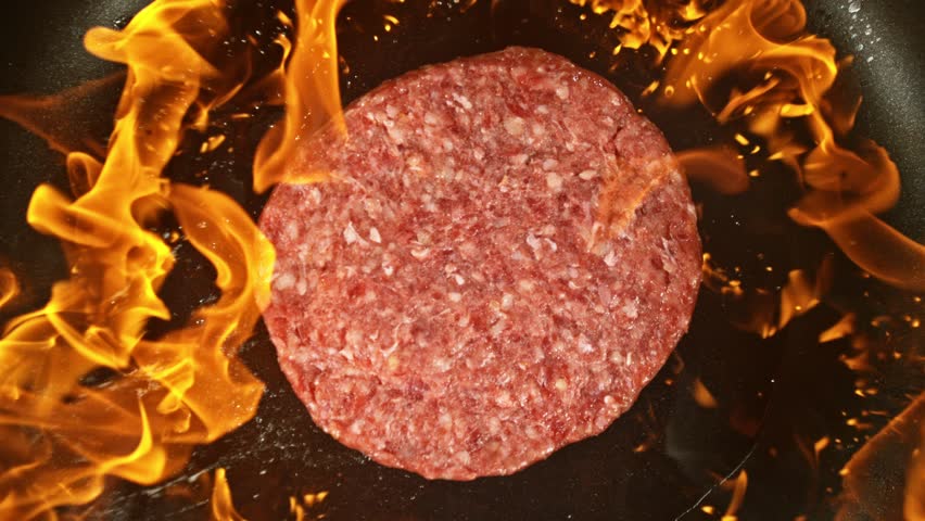 Super Slow Motion of Flying Raw Beef Hamburger Minced Meat on Pan with Fire. Shot form Above. Filmed on High Speed Cinema Camera, 1000 fps.