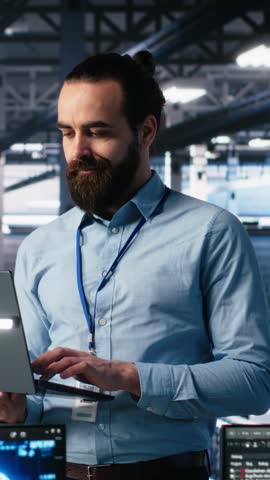 Vertical video Data center technician using laptop to monitor neural network AI LLM visualization. IT specialist in high tech facility using notebook to oversee servers powering machine learning
