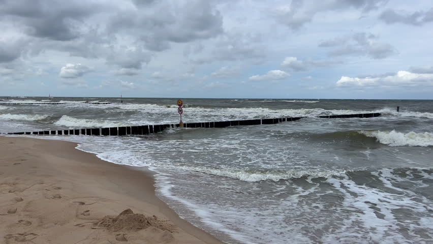 Cloudy day at the Baltic Sea, stormy waves and breakwater on the shore