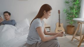 Asian young woman feel shock after look at positive pregnancy test. Disappointed unplanned pregnancy woman feel upset and worry for problem don't want to pregnant while husband lying on bed in bedroom - Powered by Shutterstock - Get 15% off with code: PIKWIZARD15
