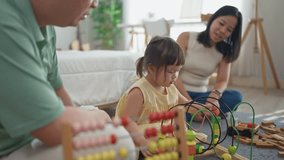 Cheerful kid girl playing with colorful toys with loving parents in house. Little adorable cute baby daughter toddler having fun, enjoy playing on soft carpet with mom and dad in living room at home. - Powered by Shutterstock - Get 15% off with code: PIKWIZARD15