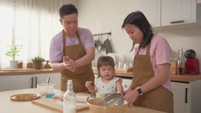 Asian mature parents lovingly care for and raises baby girl at home. Attractive couple shares tender moment teaching daughter toddler baking bakery in cozy kitchen, creating warm and nurturing family. - Powered by Shutterstock - Get 15% off with code: PIKWIZARD15