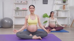 Asian two pregnant women doing yoga workout in living room at home. Attractive expectant mothers doing exercise, and stretching body for health, prepare for maternity together, part of home yoga class - Powered by Shutterstock - Get 15% off with code: PIKWIZARD15
