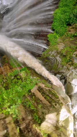 Epic FPV drone dive into powerful multi-stream Tumpak Sewu waterfall, deep green canyon, and lush rainforest in East Java, Indonesia.