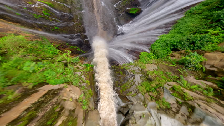 Epic FPV drone dive into powerful multi-stream Tumpak Sewu waterfall, deep green canyon, and lush rainforest in East Java, Indonesia.
