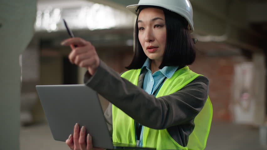Asian Korean Chinese Japanese woman holding laptop typing counting calculating builder in hard hat contractor female girl inspector engineer using digital gadget construction building plan architect - Powered by Shutterstock - Get 15% off with code: PIKWIZARD15