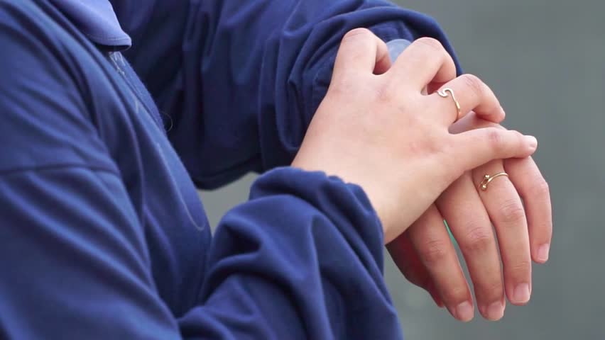 Hand close-up of a woman tapping on a smartwatch screen, showcasing modern wearable technology and touch interface on a casual outdoor setting.