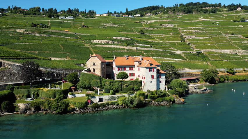 Aerial: Lake Geneva, Glerolles Castle and Lavaux terraced vineyards in the back during the day in Saint-Saphorin, canton of Vaud, Switzerland, pull out drone shot