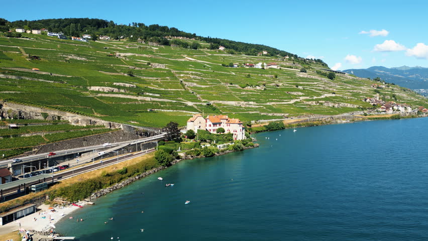 Aerial: Glerolles Castle, Lake Geneva and Lavaux terraced vineyards in the back during the day in Saint-Saphorin, canton of Vaud, Switzerland, push in drone shot
