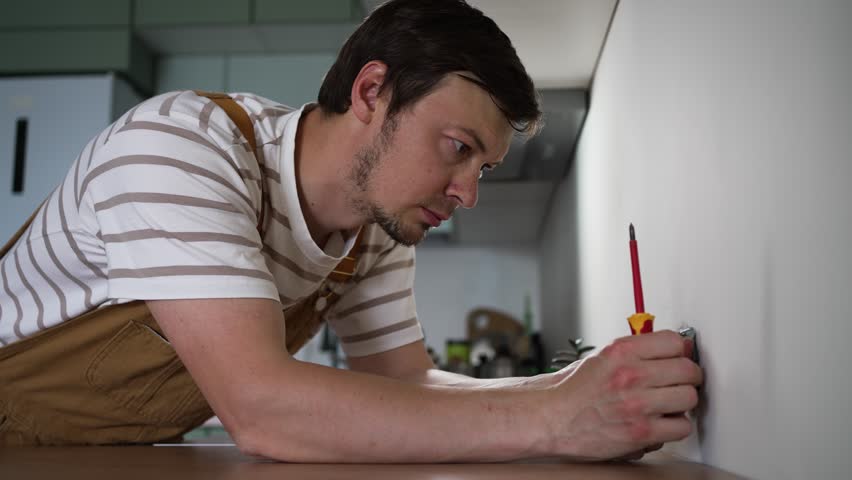 Skilled electrician installing electrical sockets, connecting wiring with precision in contemporary kitchen renovation project, showcasing professional electrical work