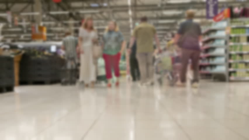 Time-lapse blurred background of crowd of people in supermarket with shopping carts