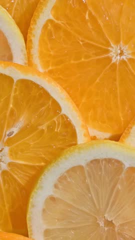 Rotating bright fresh juicy orange and lemon slices background, top view