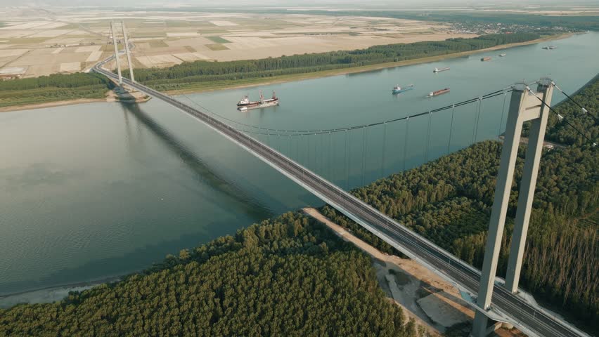 Industrial Ship Across The Danube River With Braila Bridge In Galati, Romania. Aerial Pullback Shot