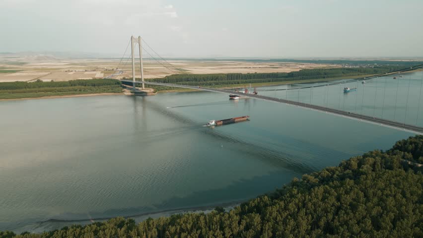 Ships Sailing Across The Danube River Under The Braila Suspension Bridge In Galati, Romania. Aerial Drone Shot