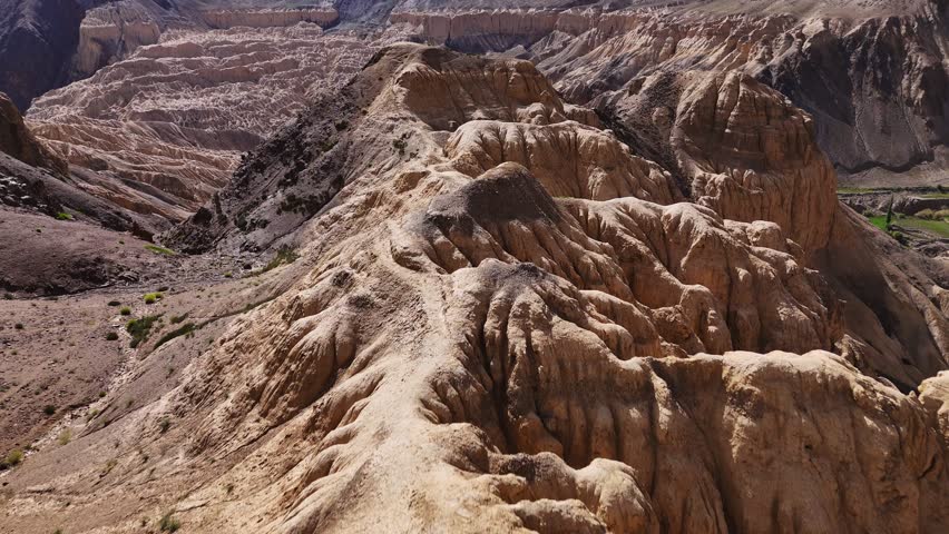 Moon like lumpy landscape in valley, Ladakh. Aerial fly over ridge revealing weaving highway through valley. India.
