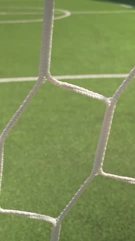 Slide shot behind empty football goal keepers net on 5-a-side pitch VERTICAL