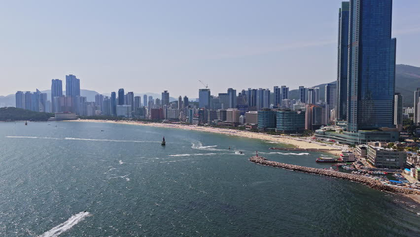Drone shot of boats and water scooters in front of the Haeundae beach, in Busan
