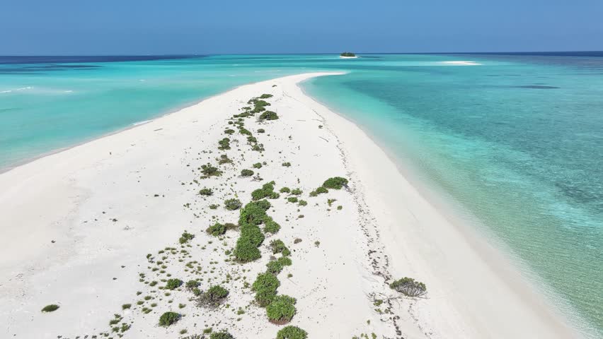 Aerial view of a pristine white sandbank meeting the turquoise waters, with a distant island adding depth, Fulhadhoo, Baa Atoll, Maldives.