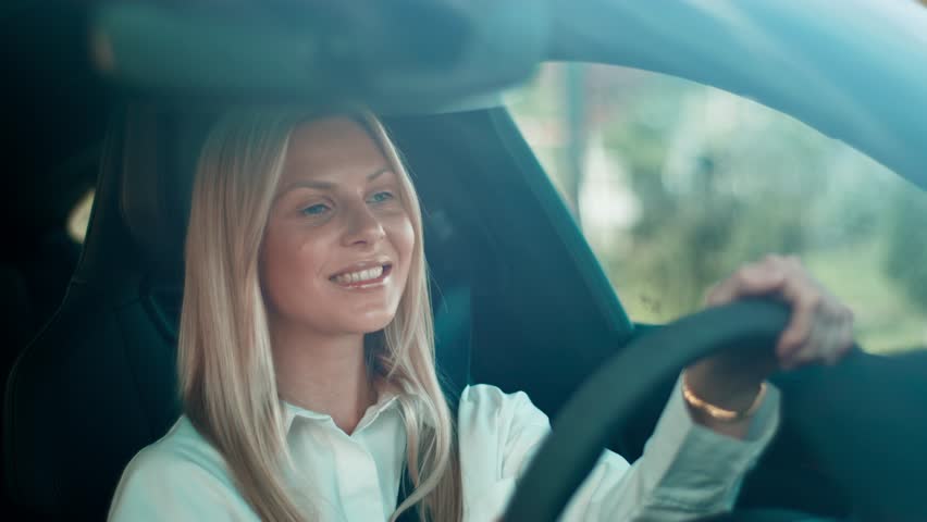 Confident pretty female with long straight hair driving car during daytime. Holding steering wheel and focusing on road. Enjoying solo trip or commuting while staying concentrated and calm.