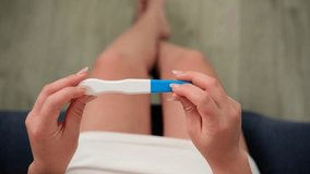 Close up of woman's hands holding pregnancy test turning to show two stripes, family planning - Powered by Shutterstock - Get 15% off with code: PIKWIZARD15