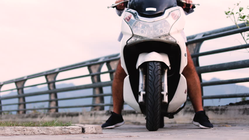 The mopeds front wheel rolls toward the camera.