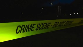 Close up or closeup of a yellow colored Crime Scene Do Not Enter police tape ribbon moving in the wind in front of a dark background with bokeh street light during evening or night time, well lit tape - Powered by Shutterstock - Get 15% off with code: PIKWIZARD15